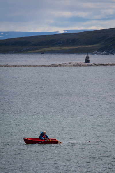 Lonely fisherman in norway checking the nets. Beinf close to the edge and sitting in a red boat in contrast to the blue surroundings, almost monochrome. Balancing it up I think quite well. I maybe should have dodged him a little to balance even better?