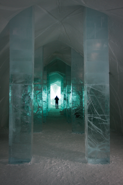 Main hall of the Ice Hotel. In the distance a single person, very small but contrasting against the white background and the pillars leading the view towards him. Symmetry was here one main goal.